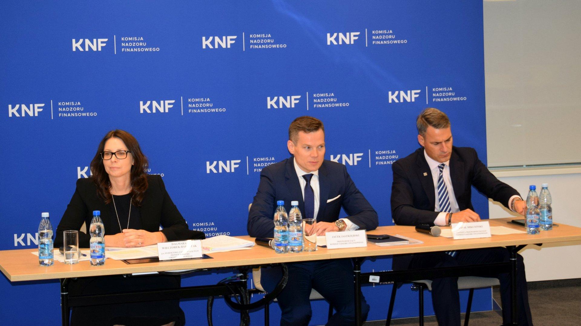 Przewodniczącego KNF, Jacek Jastrzębski; Z-ca Przewodniczącego KNF, Dagmara Wieczorek-Bartczak oraz Z-ca Przewodniczącego KNF, Rafał Mikusiński; w tle ścianka z logotypami KNF